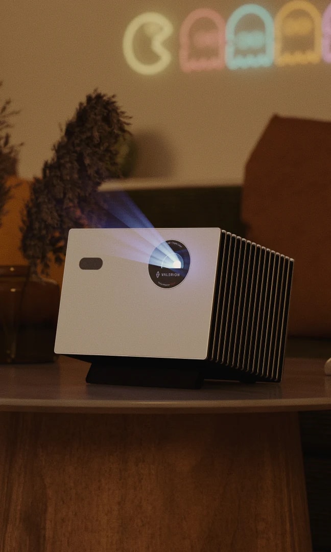 Valerion StreamMaster Plus 2 projector on a table in a cozy living room, projecting a game on the wall.