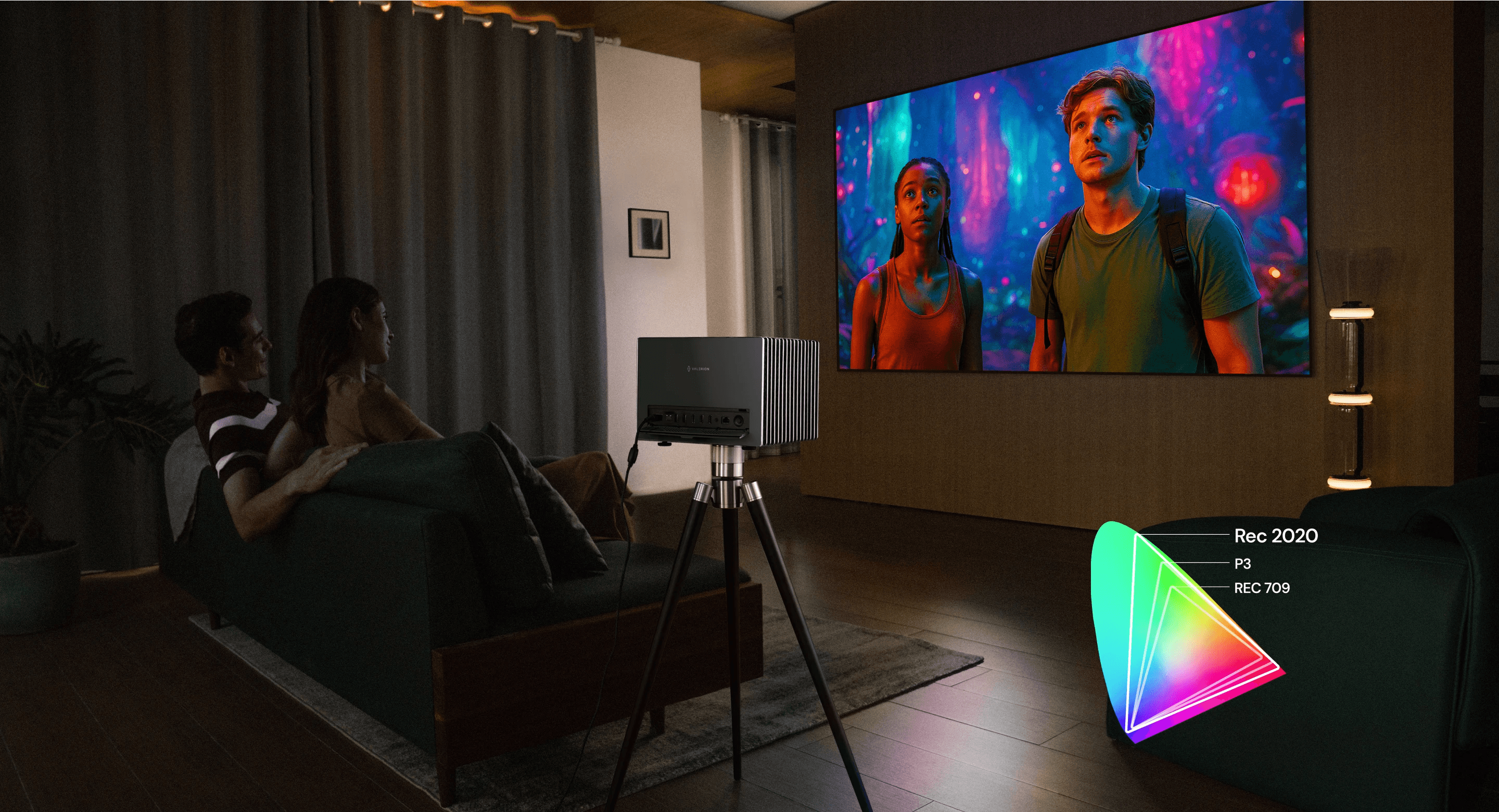 A couple in a home theater setting watching a movie via the VisionMaster Pro 2 projector on a tripod.